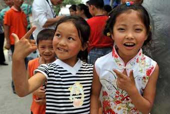 Liu Yashi (R) and her friend Deng Xiaoyu play beside a road in Qingxia village, Longmen Town, Mianyang City of southwest China's Sichuan Province, on May 27, 2008. The children live in makeshift tents after the 8.0-magnitude earthquake in Sichuan will spend their International Children's Day at their resettlements. (Xinhua Photo)