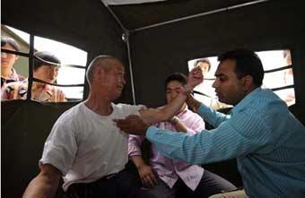 A member (R) of the Pakistani medical team does medical checkup for a man in the Wudu District of Longnan City, northwest China's Gansu Province, June 2, 2008. The 28-member Pakistani medical team has set up a tent hospital in quake-hit Longnan after it arrived in the city on May 29.(Xinhua Photo)