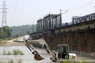 Workers are busy working beneath the Fujiang bridge which is part of the Baocheng railway in Mianyang city, southwest China's Sichuan Province, June 10, 2008. The Government of Mianyang city issued an orange alert, the second critical level after red, for possible total dam-break because the drainage of the Tangjiashan quake lake doubly sped up on June 10,2008. All the people will evacuate in planned routing if the alert rises from orange to red.(Xinhua Photo)