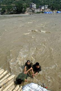 Soldiers from airborne force eliminate danger in flashy stream at Nanba Town, Pingwu County of Mianyang City, in southwest China's Sichuan Province, on June 12, 2008. The airborne troops built up a "life bridge" above a torrential stream that separate Nanba Town and the outside areas and take guard around the bridge day and night against any contingency that could break it. (Xinhua Photo)