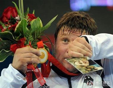 Matthias Steiner is holding his late wife's picture high which he is standing on the podium.