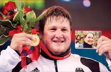 Matthias Steiner of Germany holds the gold medal he dedicated to his late wife Susann, who died in a car accident in 2007, after winning the men's +105 kg of the weightlifting competition August 19 2008. [Xinhua]