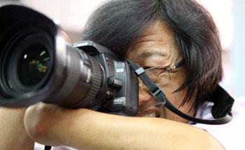 Zheng Longhua, a photographer without hands, takes pictures during a photo exhibition in Beijing, capital of China. Born in 1956 in east China's Zhejiang Province, Zheng lost his two hands in his childhood and started his career of photography in 1981.(Xinhua Photo)