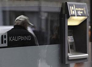 The shadow of a man is reflected on a window next to an automatic teller machine outside a branch of the Icelandic bank Kaupthing in Rejkjavik. Iceland's government nationalised the country's biggest bank, Kaupthing, on Thursday, just days after the second and third biggest banks were brought under state control.(AFP/File/Olivier Morin)