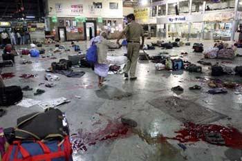 An Indian policeman escorts out a survivor from the shooting site after an attack at the Chattrapati Shivaji train station in Mumbai as blood stains the floor amid scattered luggage.(Xinhua/Reuters Photo)