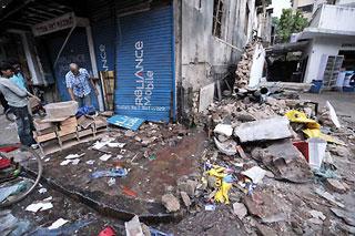 A shopkeeper cleans the shop near Nariman house where terrorist attack took place in Mumbai, India, Nov. 30, 2008. After the final siege at the Taj Mahal hotel, lives of people live in Mumbai began to return to normal. But the main areas, which were attacked by the terrorists, are still blocked by the police.(Xinhua/Liu Sui Wai)