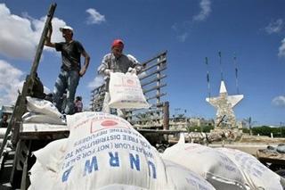 Palestinian refugees carry food aid they received from the United Nations Relief and Works Agency for Palestine Refugees in the Rafah refugee camp in the southern Gaza Strip, April 2008.(AFP/File/Said Khatib)