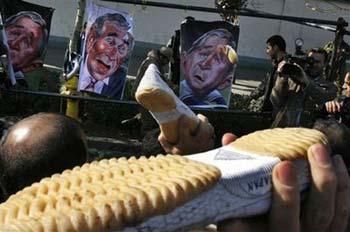 Iranian men throws shoes at posters showing caricature images of US President George W.Bush prior to Friday prayers in Tehran, Iran, Friday, Dec.26, 2008, following the lead of Iraqi shoe-throwing journalist Muntadhar al-Zeidi, who threw his shoes at the President Bush. (AP Photo/Vahid Salemi) 