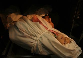 The body of a Palestinian child lay on a stretcher at Shifa hospital in the east of Gaza City after an Israeli strike on Jan. 5, 2009. (Xinhua Photo)