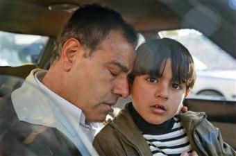 Dr. Ezzeldeen Abu al-Aish, a Palestinian doctor and peace activist who trained in Israel and became a regular fixture on Israeli television, rests his head on his son Abdullah, 6, in a car before traveling to Israel with his children, near his house in Jebaliya, in the northern Gaza strip, Wednesday, Jan. 21, 2009. Three of his daughters and a niece were killed by an Israeli shell which struck his house, and he returned to Gaza Wednesday to collect his remaining children.(AP Photo/Ben Curtis)