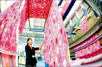 A worker checks the cloth at a workshop in Zhangjiagang City, north China's Hebei Province October 22, 2008. China will increase the tax rebate rate for textile and garment exports from 14 percent to 15 percent. [china.com]