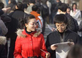 Job hunters receive materials with job vacancy information at a job fair in Beijing, on Feb. 5, 2009. Nearly 4,000 positions are offered by more than 300 companies at the job fair on Thursday. (Xinhua/Xing Guangli)