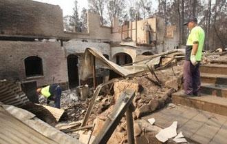 Two people sift through the burnt-out ruins of the Kerami Gardens Resort in Marysville after bushfires destroyed the town.(AFP/William West)