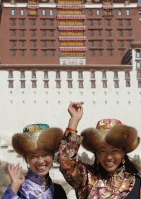 Two women pose for photos in front of the Potala Palace in Lhasa, capital of southwest China's Tibet Autonomous Region, Feb. 11, 2008.  (Xinhua/Chogo)