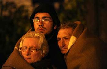 Three people cover themselves with a blanket as they take a rest in L'aquila, Italy, early April 7, 2009. The strong earthquake that hit central Italy on Monday has killed at least 179 people, injured some 1,500 and left around 70,000 homeless, Italian media reported on Tuesday. (Xinhua/Wu Wei)