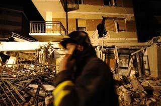 A rescuer walks past a collapsed building in L'aquila, Italy, earth April 7, 2009. The strong earthquake that hit central Italy on Monday has killed at least 179 people, injured some 1,500 and left around 70,000 homeless, Italian media reported on Tuesday.(Xinhua