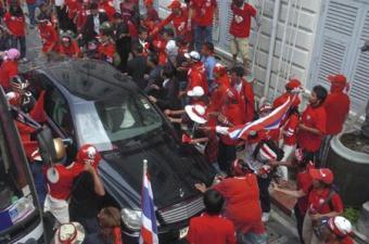 Protesters surround and beat the car carrying Thai Prime Minister Abhisit Vejjajiva at the interior ministry in Bangkok April 12, 2009. Troops fired into the air as Thai anti-government protesters stormed the country's interior ministry on Sunday after Abhisit declared a state of emergency in the capital.[Agencies]