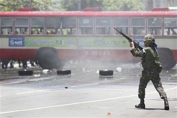 A Thai soldier fires a shot into the air as they clear anti-government protestors from the streets near downtown Monday, April 13, 2009, in Bangkok, Thailand. Thai authorities have declared a state of emergency shutting down rail service as soldiers continue to battle against anti-government demonstrators.(AP Photo/Wong Maye-E) 