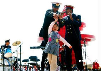A little girl dances as members of Bangladeshi navy's military band perform during a performance in Qingdao, east China's Shandong Province, April 21, 2009.(Xinhua/Li Gang) 
