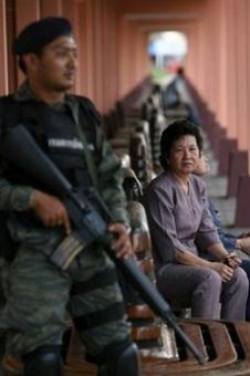 Thai passengers wait for a train watched by a soldier at a railway station in Thailand's restive southern Yala province. Suspected militants in Thailand's deep south killed nine people and injured two others in five separate attacks on the eve of a key anniversary for the restive region, police said.(AFP/File/Muhammad Sabri)