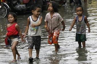 File photo shows Filipino children playing in floodwaters near the the shores of Manila Bay. Flooding and landslides triggered by heavy rains have left 20 people dead in the eastern Philippines, officials said. (AFP/File/Luis Liwanag) 