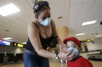 A woman adjusts a face mask on a child as a precaution against swine flu as they wait for their baggage at the Jorge Chavez airport in Callao, Peru Thursday, April 30, 2009.(AP Photo/Karel Navarro)