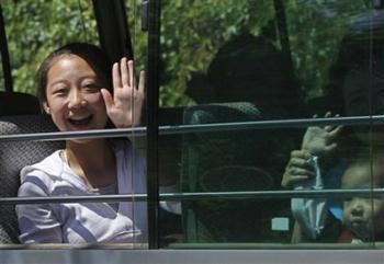 A woman waves after being released from quarantine at a holiday camp where they were held for a week in Hong Kong Thursday, May 7, 2009. At least 28 of the 34 passengers who flew from Shanghai to Hong Kong with the Mexican man confirmed as the territory's first and only swine flu patient were released Thursday afternoon. Another 347 guests and staff quarantined in the Metropark Hotel in Wanchai will be released Friday evening.