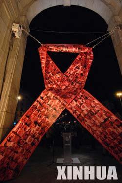 A large red ribbon printed with human faces is hung on the Alcala Gate for the upcoming World AIDS Day, in downtown Madrid, capital of Spain, Nov. 30, 2008.(Xinhua photo)