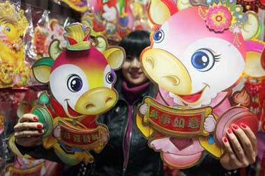 A girl shows New Year decorations in the shape of ox at a wholesale market in Beijing, capital of China, Jan. 3, 2009. As the Chinese lunar New Year approaches, Spring Festival decorations are becoming popular. The Chinese lunar New Year will start from Jan. 26 this year. (Xinhua Photo)