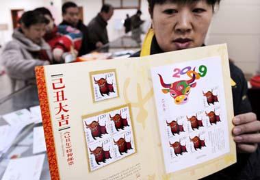 A postal official shows stamps marking the Chinese traditional lunar Jichou Year of 2009 at a post office in Qingdao, east China's Shandong Province on Jan. 5, 2009. The stamps, with the image of ox marking the Jichou Year of 2009, was issued by the State Post Bureau nationwide on Monday. ( Xinhua Photo)