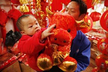 A child touches a doll cow bought by his father at a market in Guiyang, capital of southwest China's Guizhou Province, Jan. 13, 2009. People were busy in selecting decorations and goods to greet the Chinese traditional Spring Festival, which falls on Jan. 26 this year.(Xinhua/Qin Gang)