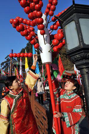 Workers in ancient Chinese dress decorate the street with mock Tanghulu, a Beijing's traditional snack made of sugarcoated haws and other fruit on a stick, for the royal temple fair in the Summer Palace in Beijing, Jan. 18, 2009. Visiting temple fairs, or 
