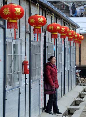 A woman walks out of a temporary dwelling decorated with red lanterns in Chenjiaba Township of Beichuan County, southwest China's Sichuan Province, Jan. 20, 2009, before the Chinese lunar New Year starts from Jan. 26. Beichuan was one of the areas hit most seriously by the May 12 earthquake last year. (Xinhua/Li Xiaoguo)