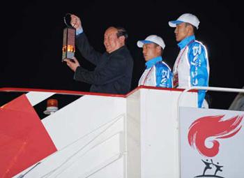 Jiang Xiaoyu (L), the executive vice president of the Beijing Organizing Committee for the 2008 Olympic Games (BOCOG), walks out of the cabin with the lantern which holds the Olympic flame in his hands at the airport in St. Petersburg, Russia, April 4, 2008. St. Petersburg is the third stopover of the 2008 Beijing Olympic Games flame relay outside the Chinese mainland. [Xinhua]