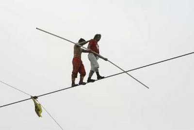 Alfred Nock Junior (R) of Switzerland helps Ya Kefujiang Maimitili of China after Ya dropped his bar during the speed race of the 2009 Hangang High Wire World Championship in Seoul, in which participants cross the Han River on a 1 km (0.62 miles) wire, May 10, 2009. A total of 20 high-wire walkers from 12 countries participated in the event which is part of the annual "Hi Seoul Festival" organised by Seoul City.REUTERS/Jo Yong-Hak (SOUTH KOREA SOCIETY) 