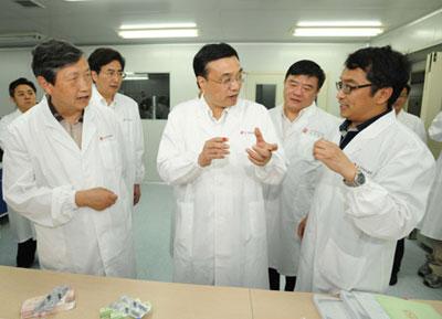 Chinese Vice Premier Li Keqiang (C) talks with a staff member of Sinovac, known in China as Beijing Kexing Bioproducts Limited Company, in Beijing, capital of China, on May 29, 2009. Li Keqiang urged vaccine companies to step up the preparation work for vaccine production after the first domestic A/H1N1 influenza case was confirmed in southern Guangdong Province Friday. (Xinhua/Ma Zhancheng)