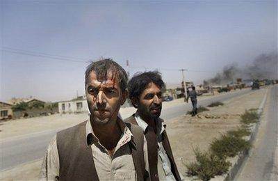 Injured Afghan men leave the scene of a suicide car bomb attack in on the outskirts of Kabul on Tuesday Aug. 18, 2009. A suicide car bomber attacked a NATO convoy killing at least seven civilians and wounding 50 people, including several international troops, officials said. A U.N. spokesman said three U.N. staff were also wounded.(AP Photo/David Guttenfelder) 