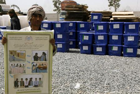 An Afghan election worker shows an election poster at the independent election commission office in Kandahar province August 17, 2009(Xinhua/Reuters Photo)