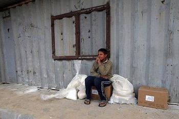 A Palestinian boy sits on food aid received from the United Nations Relief and Works Agency (UNRWA) at the refugee camp of Rafah in the southern Gaza Strip on the border with Egypt. The main UN agency operating in the Gaza Strip halted its operations on Thursday after an attack on a truck convoy and amid mounting calls for Israel to abide by international humanitarian law.(AFP/Said Khatib)