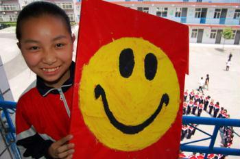 A girl shows a board with a smiling face during an activity to celebrate the upcoming World Smile Day at No. 10 Middle School in Xingtai, north China's Hebei Province, May 7, 2009. The World Smile Day falls on May 8. (Xinhua/Chen Lei)