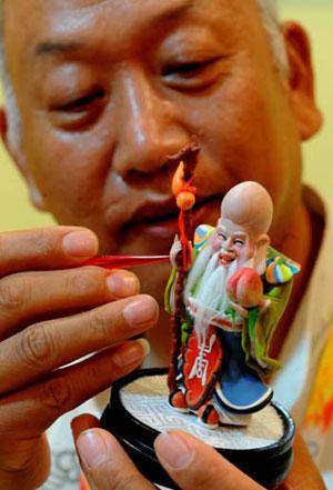 Folk sculptor Zhang Junxian carves flour figurine at the Olympic Village in Beijing, China, July 27, 2008. 27 Chinese folk artists were selected to demonstrate their skills in the Olympic Village, the athletes' compound for the Beijing Olympics. (Xinhua/Zhang Guojun)