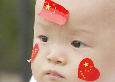 A baby with Chinese flag stickers on its face sits inside the Olympic Village at the Beijing 2008 Olympic Games, August 6, 2008. [Agencies]