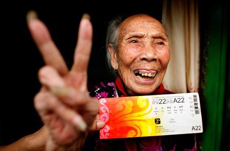 Xiao Xincui, 98, gestures with a Beijing Olympic ticket while sitting on her tricycle in Beijing on August 6, 2008. Her grandson, Liu Xianghui, has taken her to watch the Olympics by riding the tricycle from Hunan Province. [Photo: Rednet.cn]