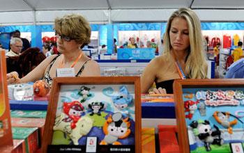 Foreign tourists buy Olympic souvenirs in the commercial and cultural street of the Beijing Olympic Village on August 20, 2008.