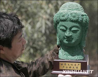 Li Mingfu(L), with the Mass Art Centre of Luoyang City, Henan Province, displays his work -- a replica of Buddha Losana statue which is located in the Longmen Grotto of the same provice, April 6, 2009. (Xinhua Photo)