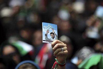 A woman holds a picture of Iranian President and candidate for the upcoming presidential election Mahmoud Ahmadinejad as he addresses supporters in front of the Sharif University in Tehran June 10, 2009.REUTERS/Damir Sagolj