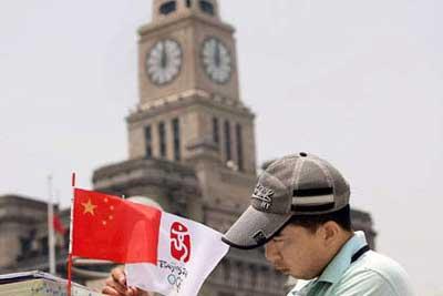 A man holds an Olympic flag yesterday at the Bund. The Beijing Olympic torch relay will be held in Shanghai tomorrow and on Saturday when traffic limits will be enforced. Century Park and the Shanghai Science and Technology Museum in Pudong will be closed tomorrow.(Photo: Shanghai Daily)