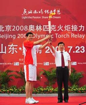 The Olympic torch was relayed in Jinan, capital city of Shandong Province on July 23, 2008. The first torchbearer Gong Xiaobin (L) receives the torch at the launching ceremony.(Xinhua Photo)