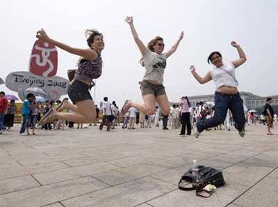 Brazilian tourists (L-R) Rayana Ueda, Tarsila Arruda and Silvia Lei jump in front of a 2008 Olympic sign in Beijing's Tiananmen Square on August 5, 2008. The tourists from San Paulo were being photographed by a friend. [Agencies]