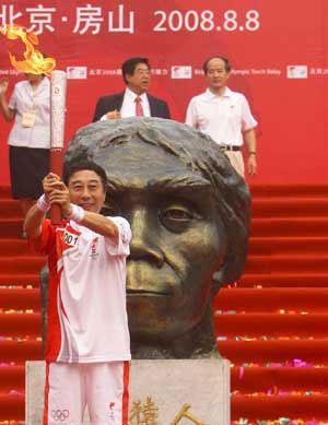 The first torchbearer Feng Gong holds up the torch at the start of the last-day of Beijing Olympic Games torch relay in Zhoukoudian of Beijing, China, Aug. 8, 2008. The Olympic torch started its final-hours relay on Friday morning at Zhoukoudian, an UNESCO heritage site in southwestern Beijing suburb which has yielded many archaeological discoveries. (Xinhua Photo)